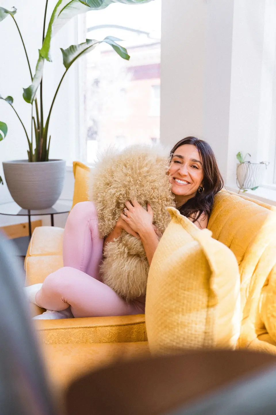 Model with a fluffy dog on the gold sofa during a lifestyle shoot