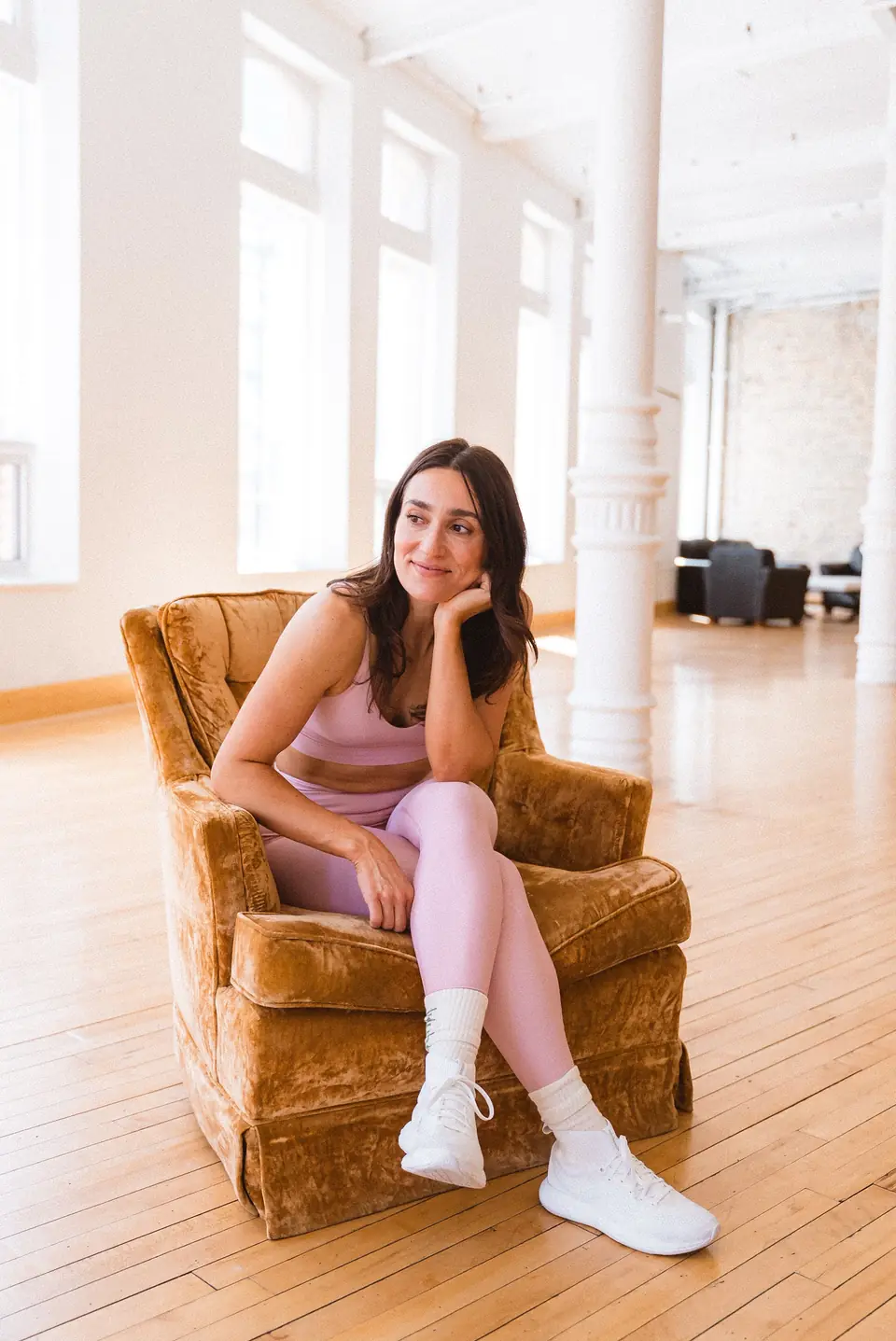 Model seated in a velvet armchair during a brand shoot