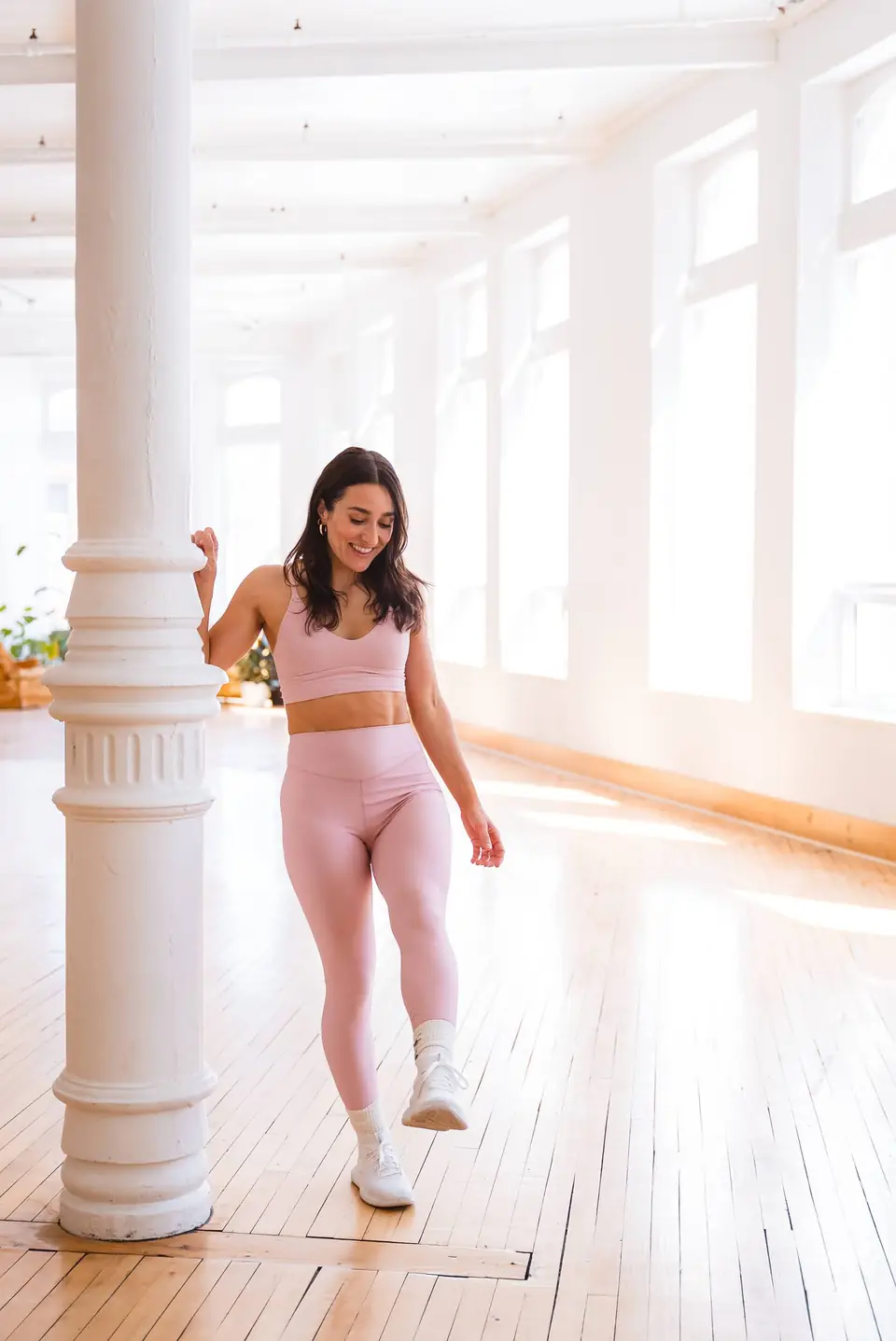 Activewear model walking past white columns and tall windows