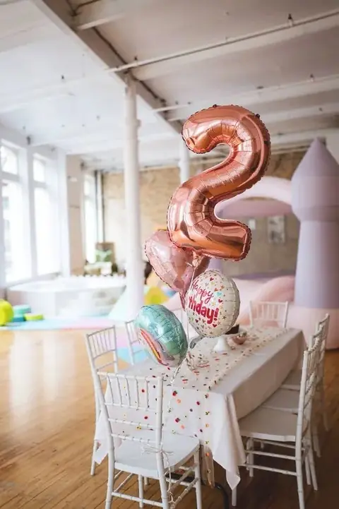 Celebration table with a number balloon, cake and white chairs