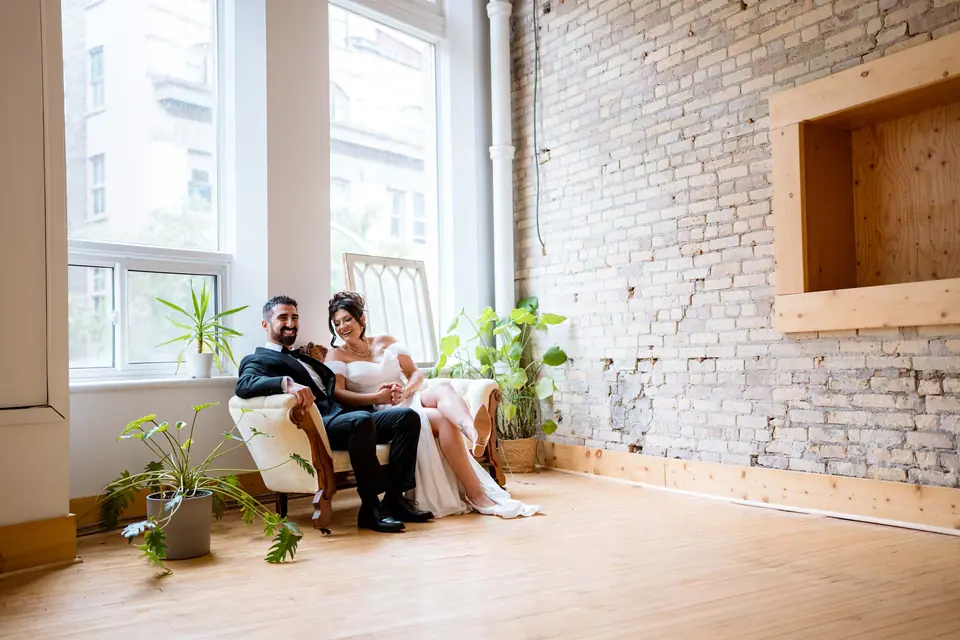 Bride and groom seated on an antique chaise by the windows