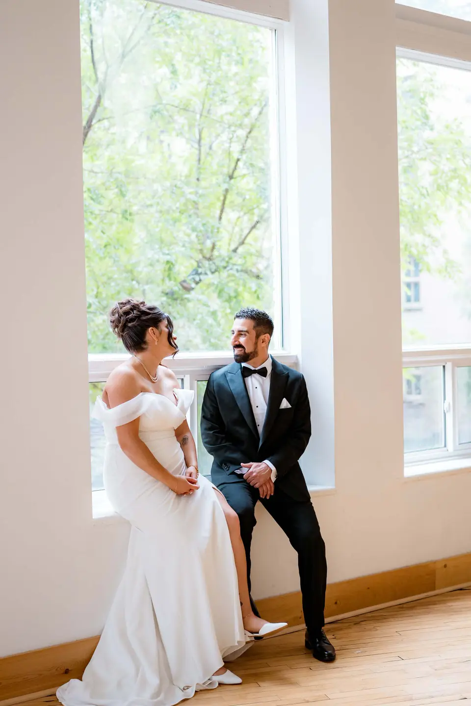 Bride and groom portrait in soft light beside the tall windows