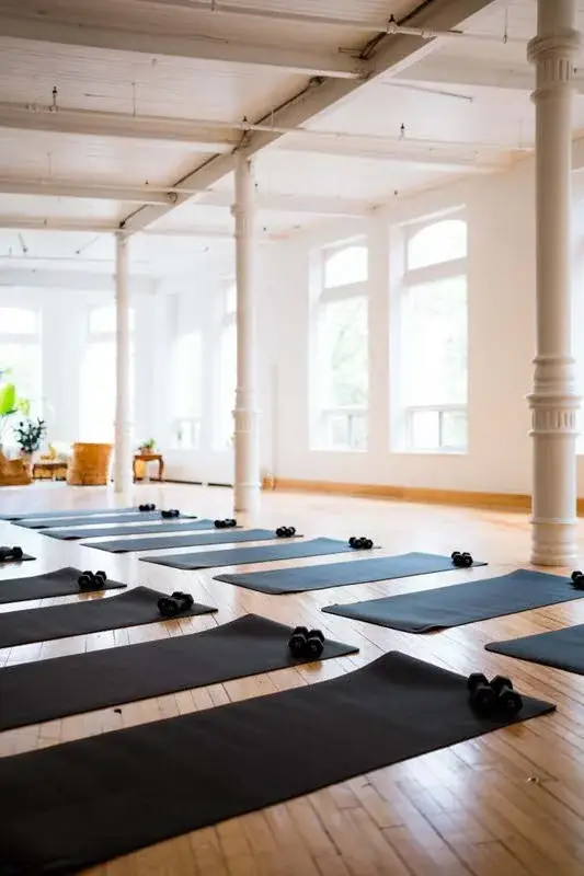 Yoga mats and dumbbells set out in rows across the main hall