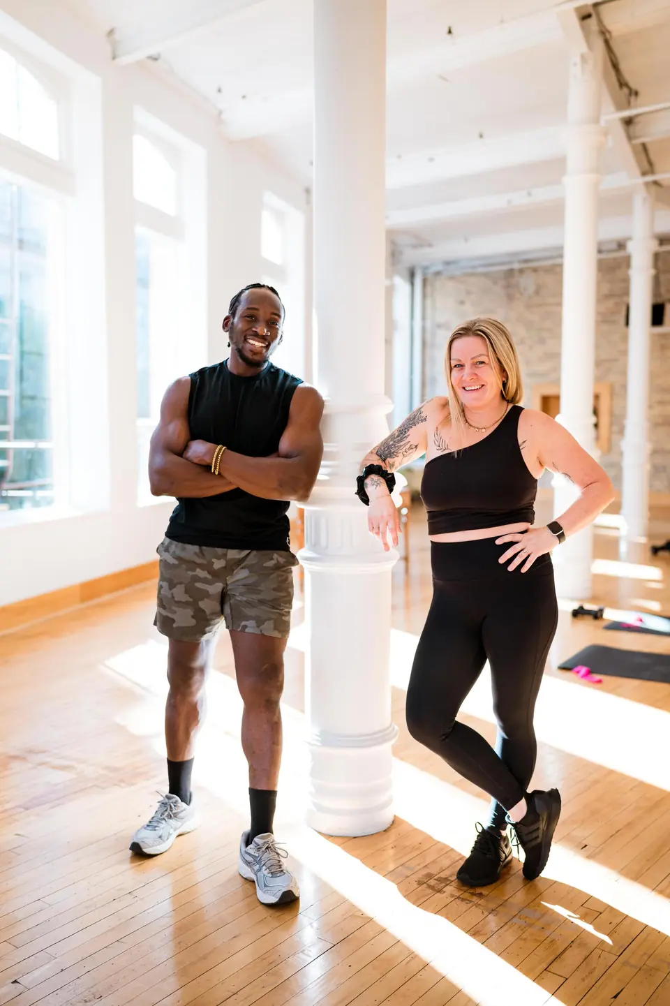 Two personal trainers posing by a white column