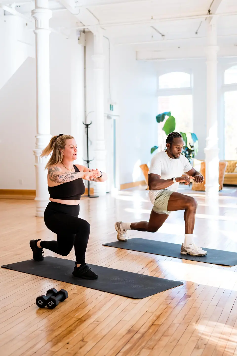 Trainers demonstrating lunges on mats during a workshop