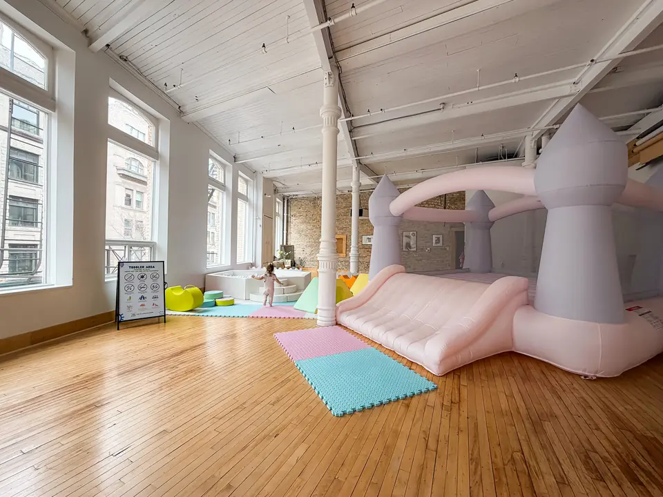 Pastel bounce castle and play mats set up in the main hall for a kids party