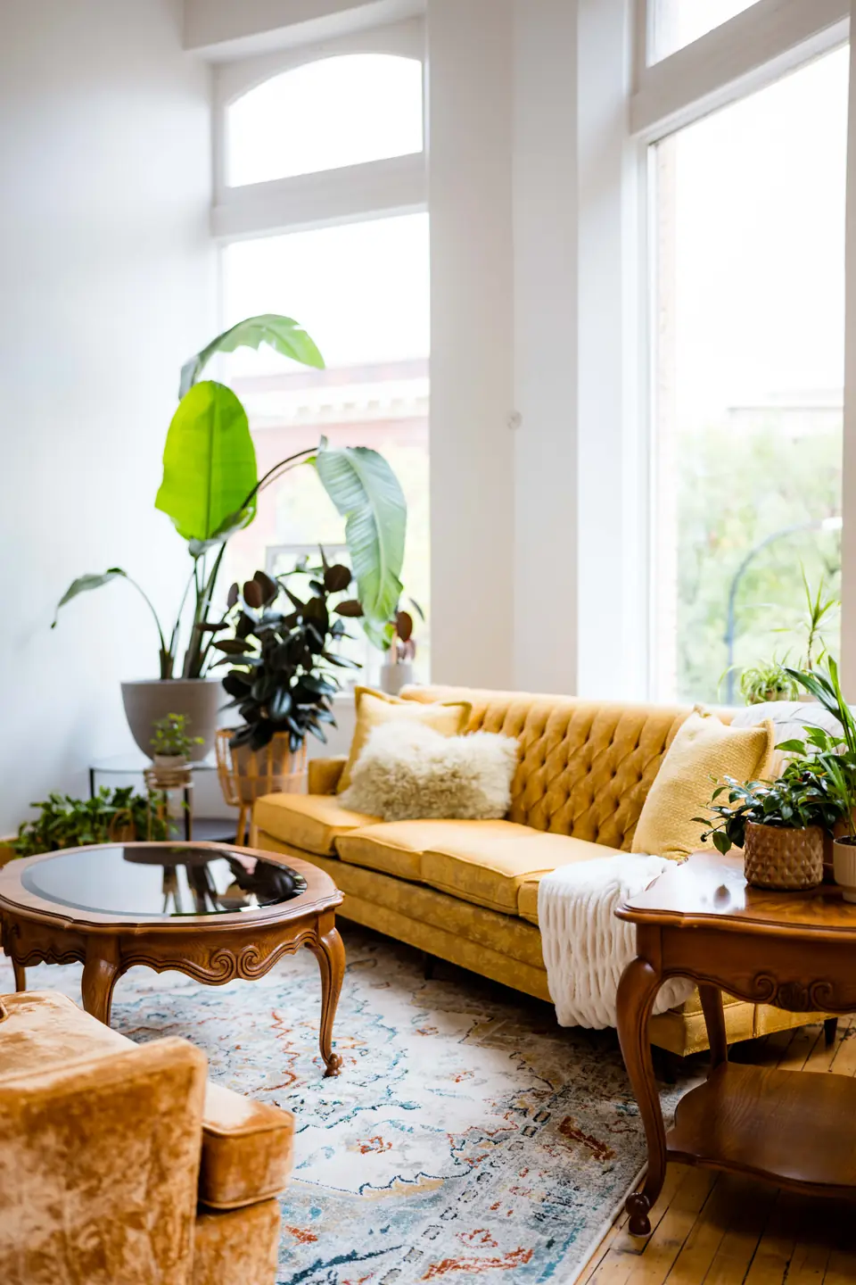 Gold tufted sofa, armchair and plants in the sunlit lounge corner