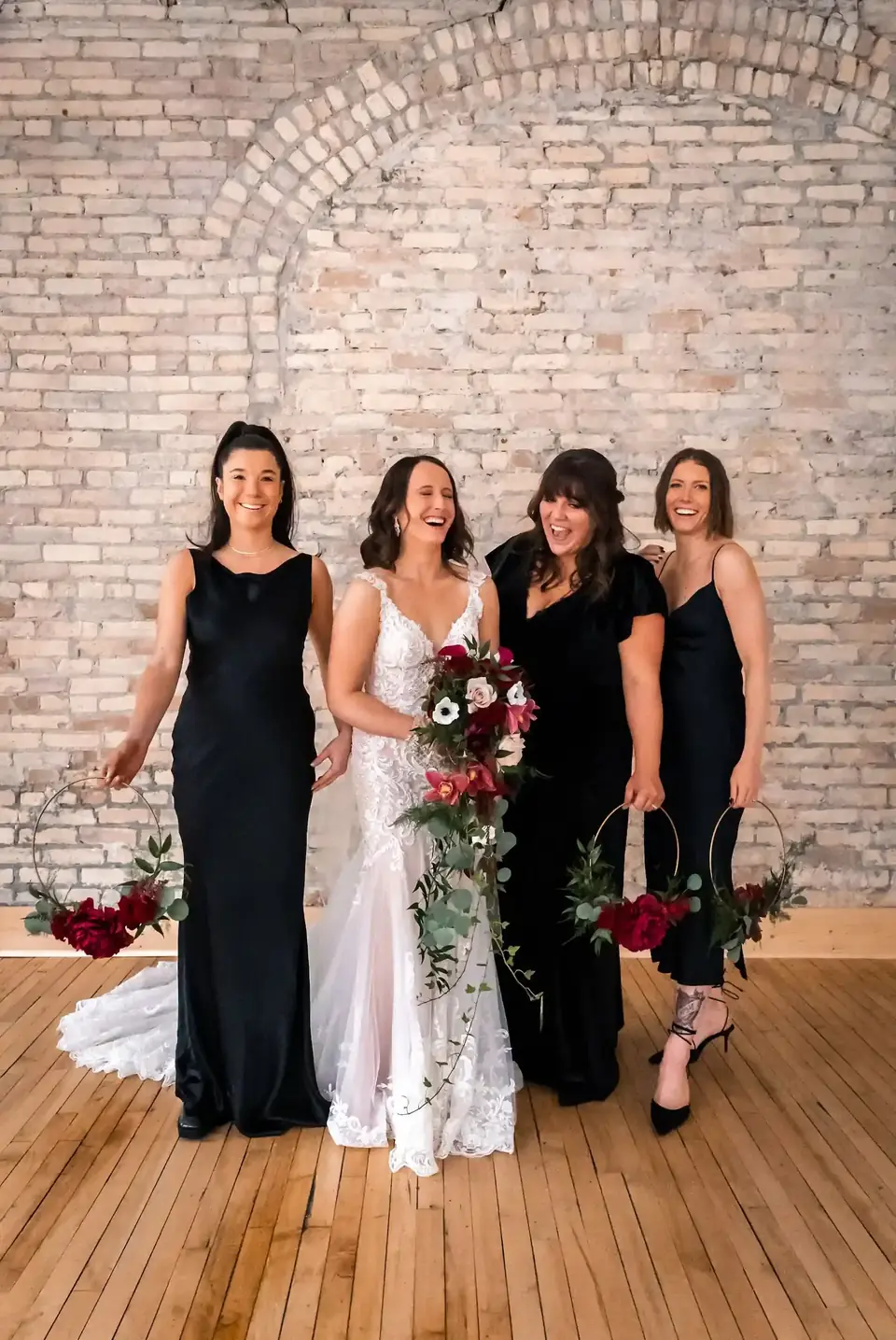 Bride and bridesmaids laughing in front of the exposed brick wall