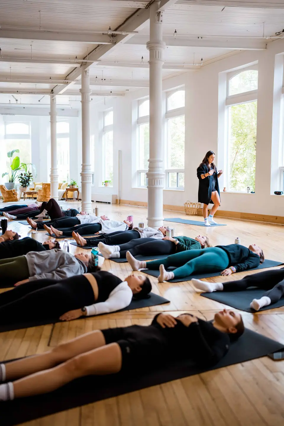 Yoga students resting in savasana on mats in the main hall